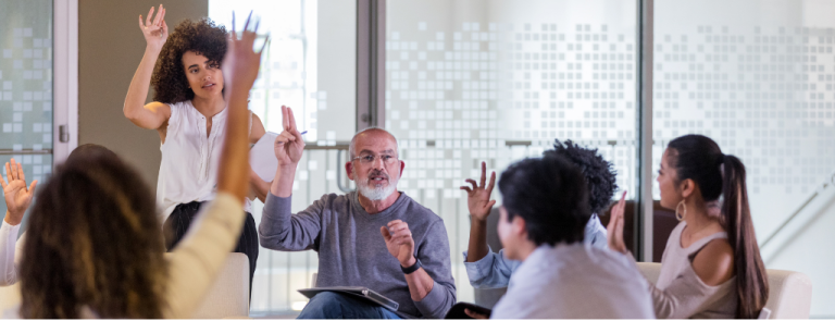 Assemblée générale de copropriétaires à Lloret de Mar, avec des participants levant la main pour voter lors d'une réunion gérée par le syndic Gabinet Senia Associats.